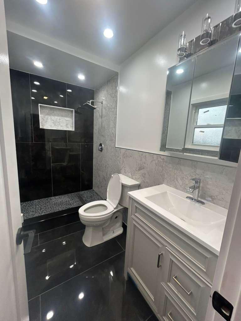 Modern remodeled bathroom with dark tile shower