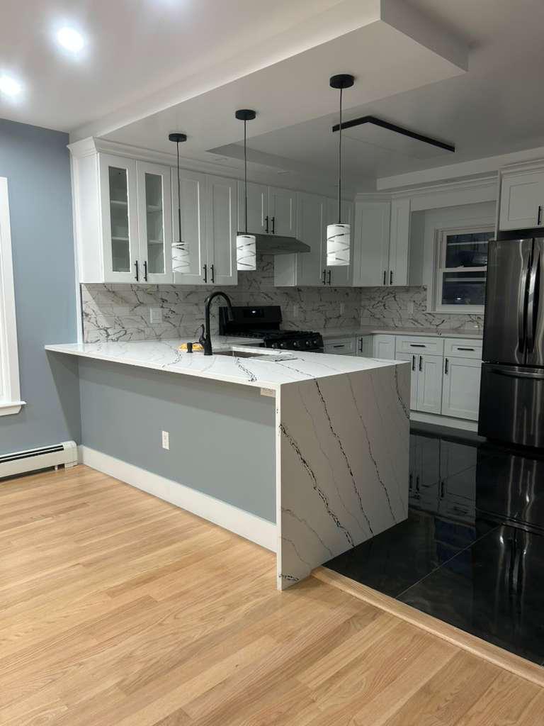Remodeled kitchen with white cabinetry and stone counters