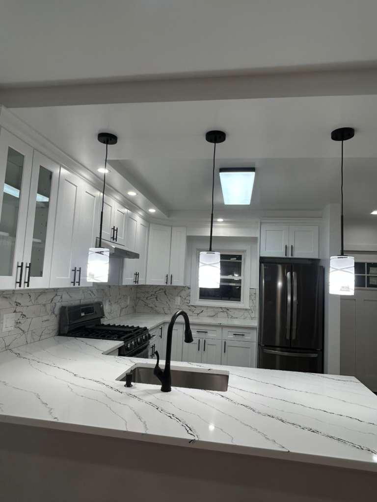 Remodeled kitchen with marble counters and stainless appliances by M2J