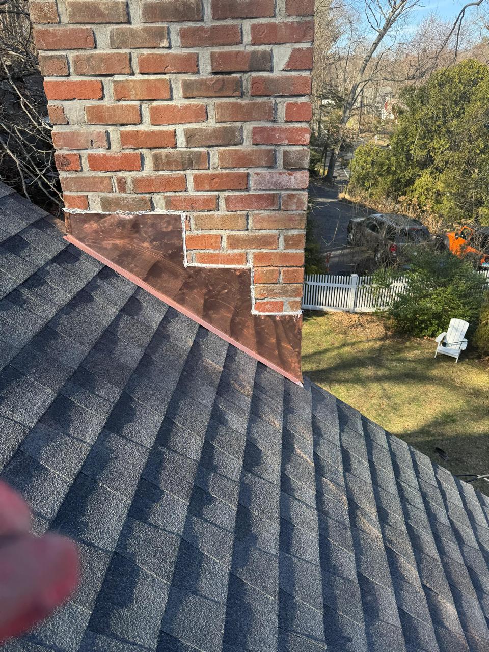 Close inspection of shingles at a brick chimney on an M2J roof