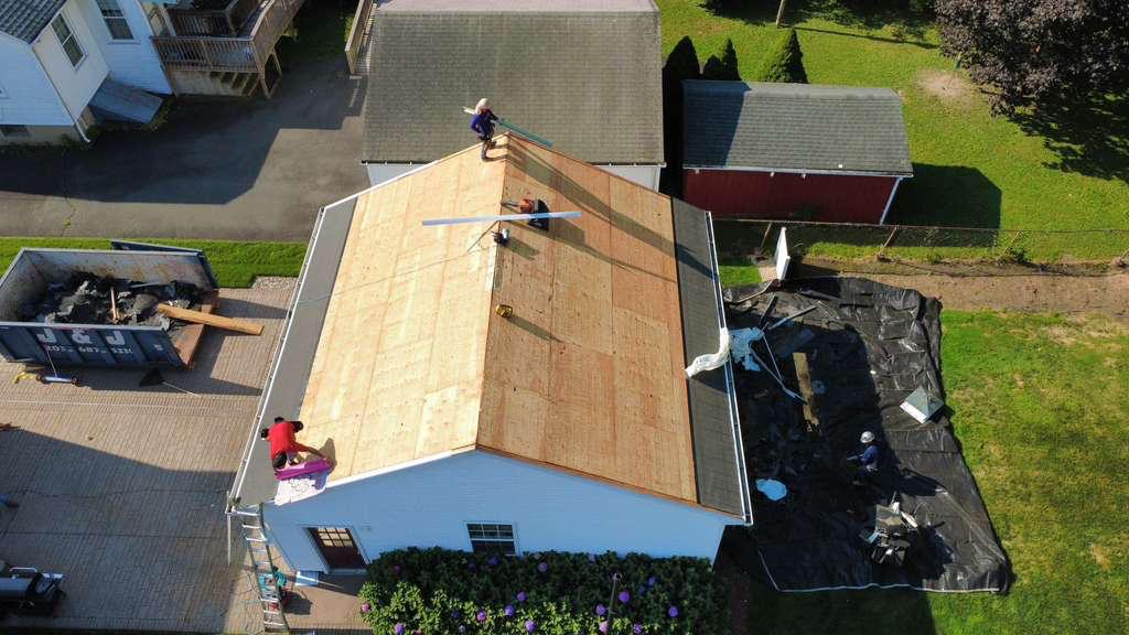 Roof mid-project with the deck exposed beside a red barn