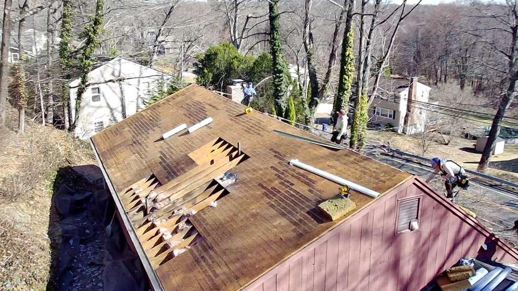 Aerial of a roof torn down to the deck with underlayment going on