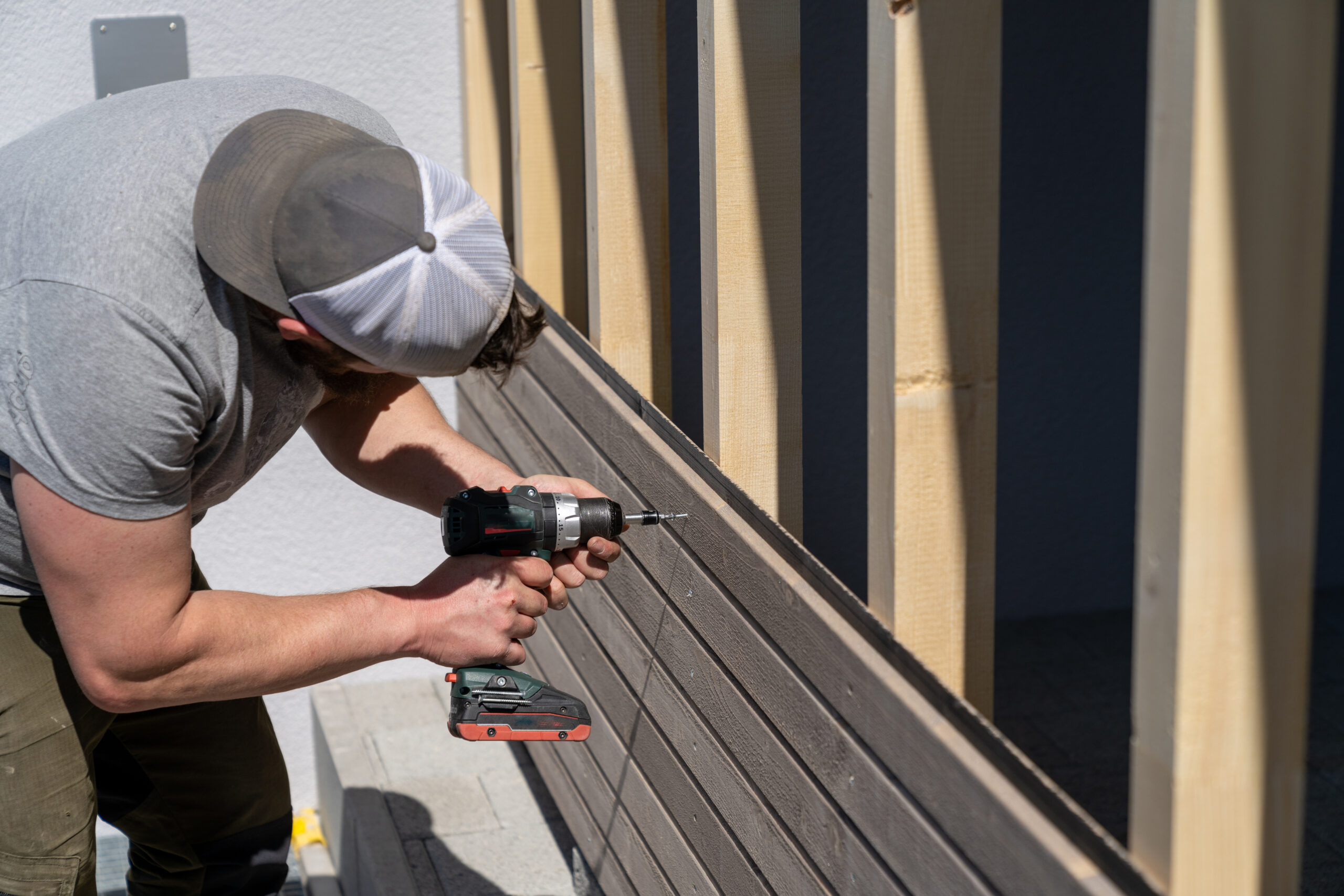 Contractor fastening wood siding to a home exterior