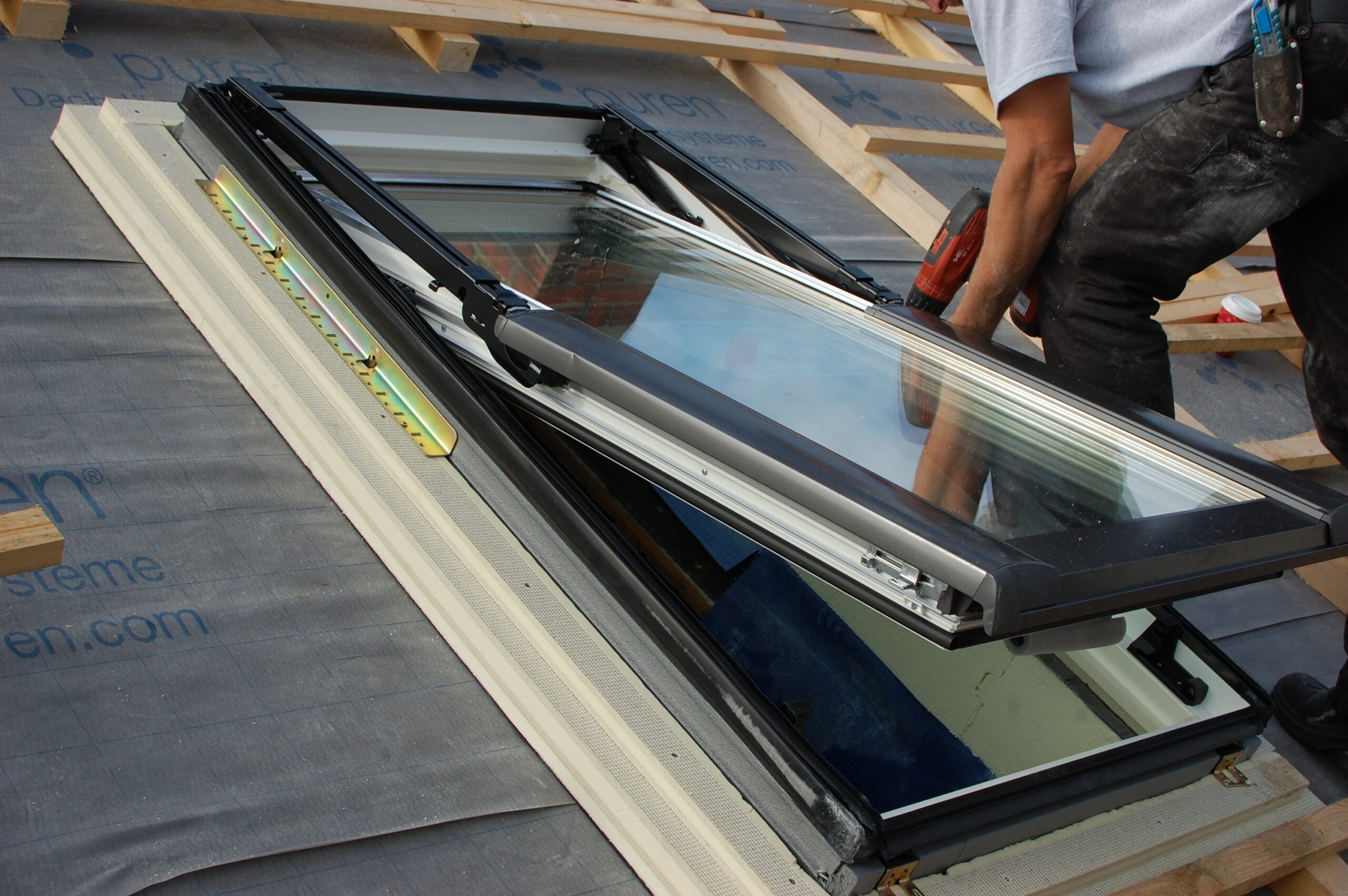 Roofer fitting a new roof-window skylight into a shingle roof